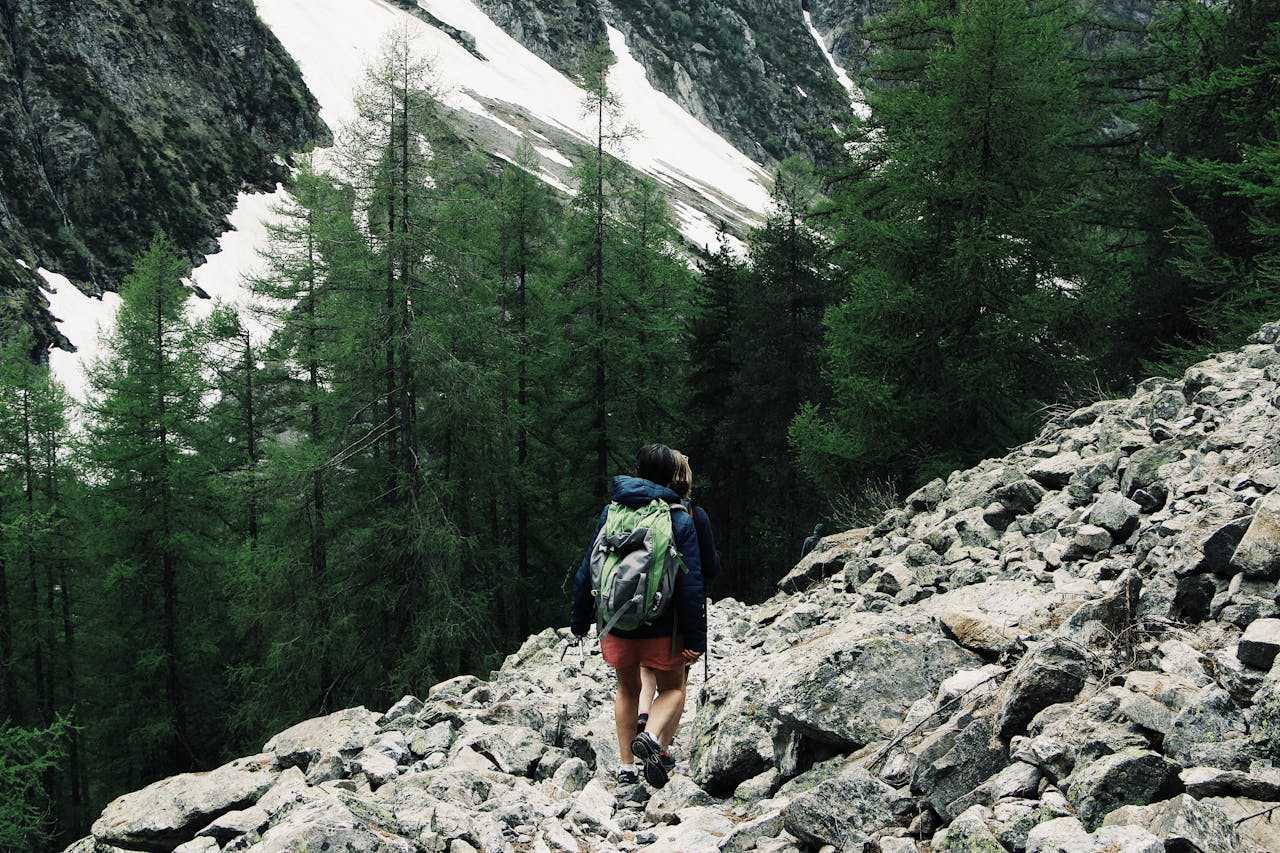 A backpacker hiking through rocky terrain in Champoléon, France with snowy peaks.