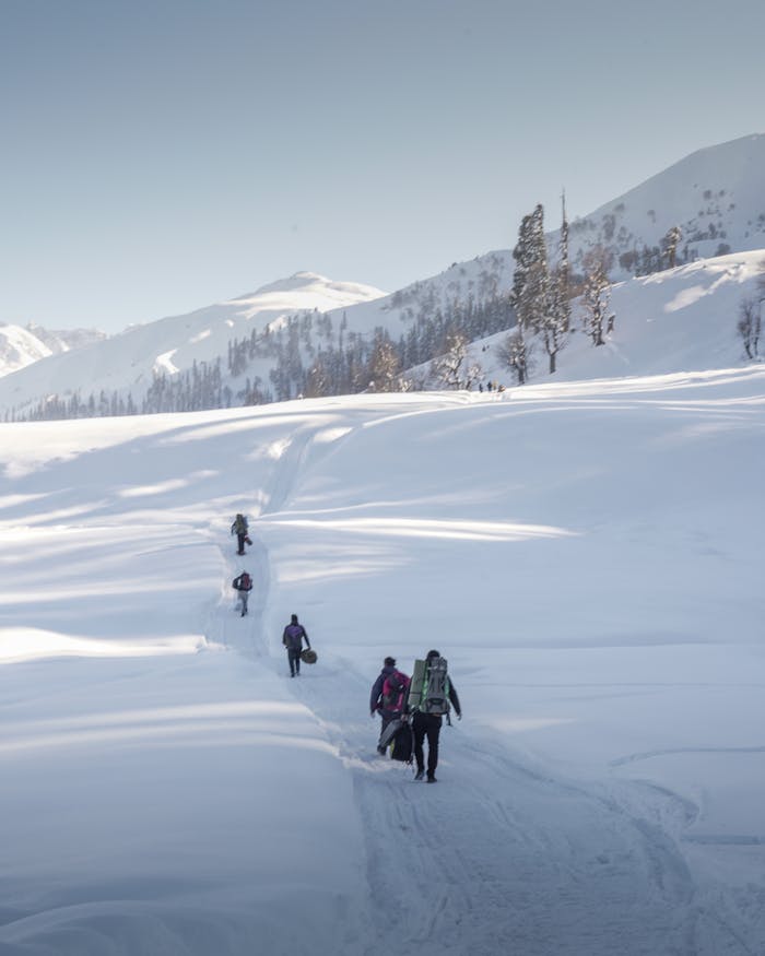 Hikers trekking through snowy mountains in Gulmarg, Kashmir, capturing adventure and exploration.